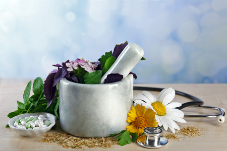 Alternative medicine herbs and stethoscope on wooden table, on light backgroundの写真素材