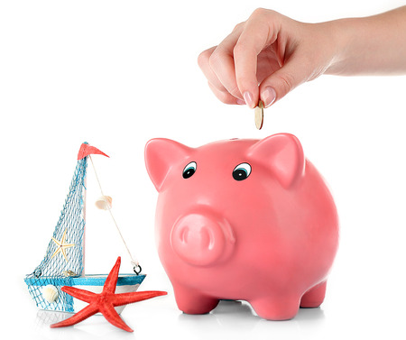 Hand inserting money into piggy bank isolated on whiteの写真素材