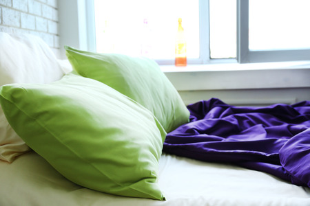 Comfortable bed with pillows and blanket in bedroomの写真素材