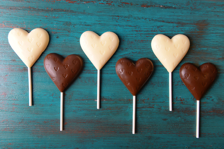 Chocolate heart shaped candies on sticks on wooden backgroundの写真素材