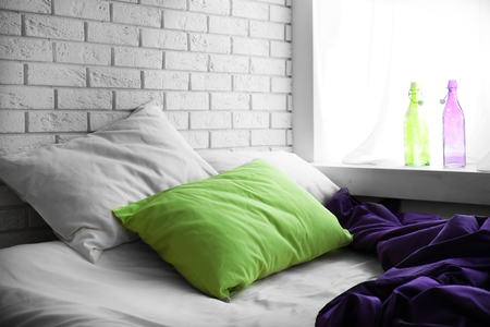 Comfortable bed with green pillow and purple blanket  in bedroomの写真素材