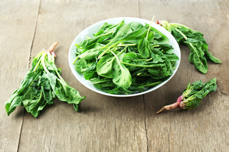 Bowl of fresh spinach leaves on wooden backgroundの写真素材