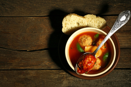 Tomato soup with meat balls on wooden spoon on wooden backgroundの写真素材