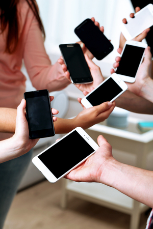Many hands holding mobile phones close upの写真素材