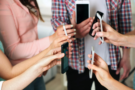 Many hands holding mobile phones close upの写真素材