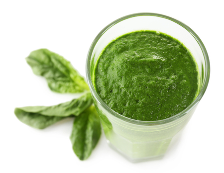 Glass of green vegetable juice with basil isolated on whiteの写真素材