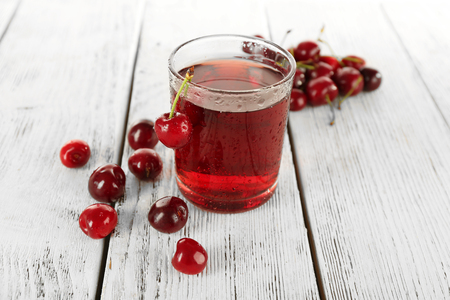 Glass of fresh juice with cherries on wooden table close upの写真素材