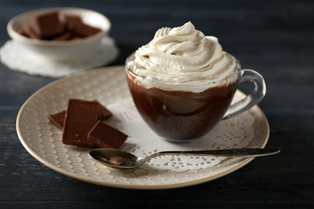 Cup of coffee with cream on color wooden backgroundの写真素材