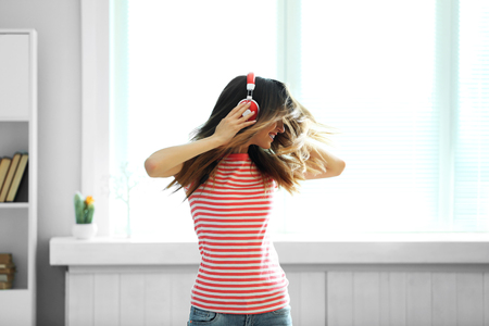 Woman listening music in headphones on windowsill backgroundの写真素材