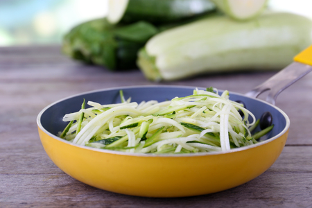 Grated zucchini and squash in pan on wooden table close upの写真素材