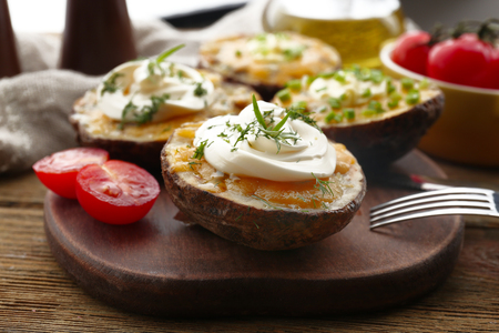 Baked potato with mayonnaise and herbs on wooden cutting board, closeupの写真素材