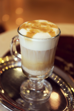 Glass of latte coffee on metal tray in cafe