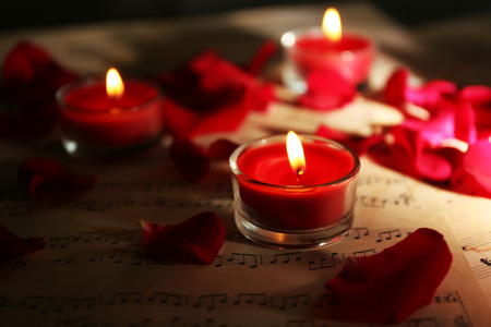 Beautiful rose petals with candles on music sheets, closeupの写真素材