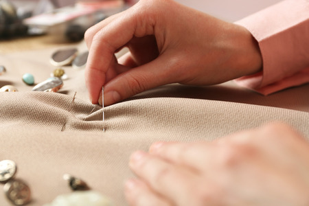 Closeup hands of seamstress at work with cloth fabric