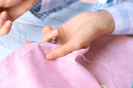 Closeup hands of seamstress at work with cloth fabricの写真素材