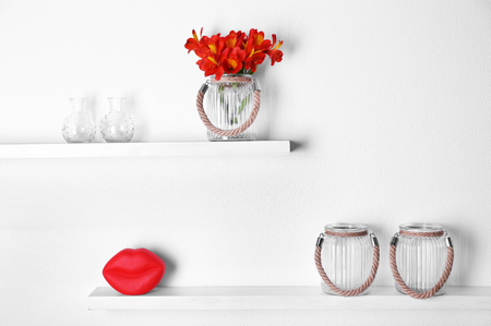 Decorative glass vases with flowers  on wooden shelf  on white wallpaper backgroundの写真素材