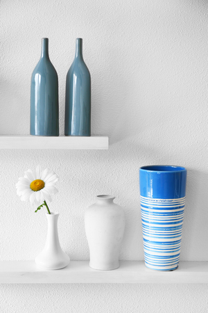 Decorative vases with flower on wooden shelf  on white wallpaper backgroundの写真素材