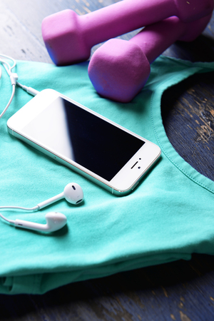 Mobile phone and earphones with set for sports on wooden table, closeupの写真素材