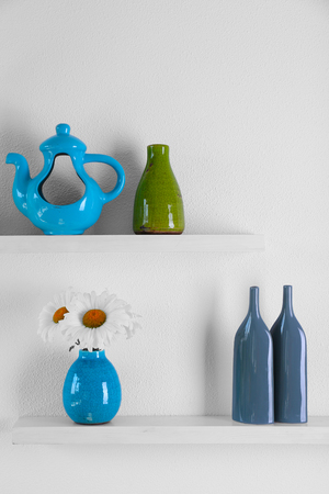 Decorative vases with flowers on wooden shelf  on white wallpaper backgroundの写真素材