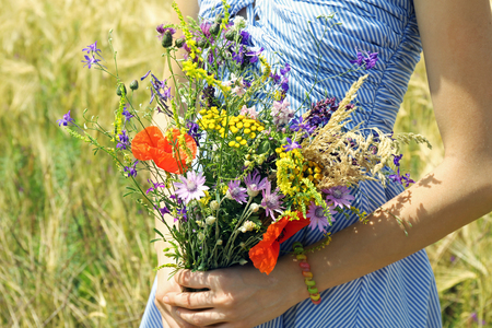 Woman holding beautiful bouquet of wildflowers outdoorsの写真素材