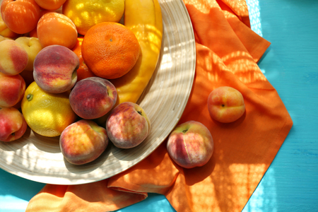 Heap of fresh fruits on tray on wooden table close upの写真素材