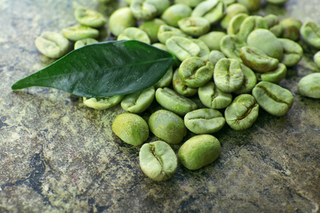 Heap of green coffee beans with leaf on table close upの写真素材