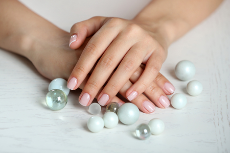Woman hands with french manicure and glass beads on table close-upの写真素材