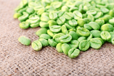 Heap of green coffee beans on sackcloth close upの写真素材