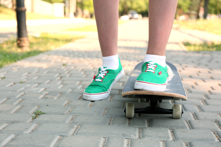 Young skateboarder in gumshoes standing on skateの写真素材