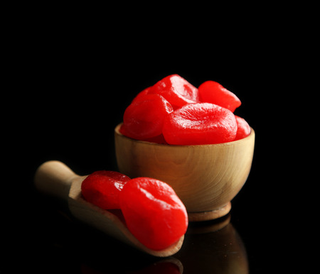 Dried kumquat fruits in wooden bowl, isolated on blackの写真素材