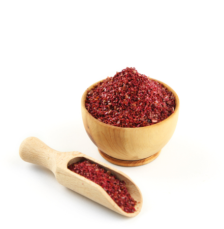 Sumac in wooden bowl, isolated on whiteの写真素材