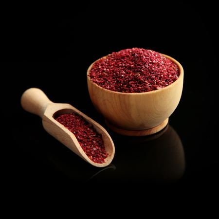 Sumac in wooden bowl, isolated on blackの写真素材