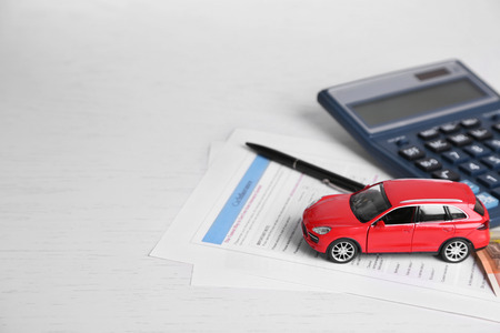 Toy car, money, documents and calculator on table. Car insurance conceptの写真素材