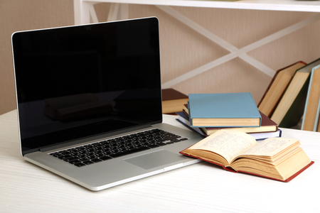 Laptop with books on table in roomの写真素材