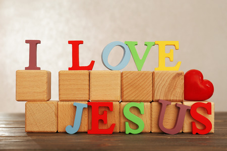 I LOVE JESUS sign illustrated with colorful plastic letters on wooden table on light textured backgroundの写真素材
