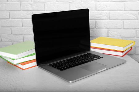 Laptop with books on brick wall backgroundの写真素材