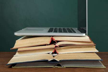 Stack of books with laptop on table in classroomの写真素材