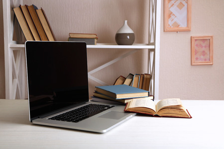Laptop with books on table in roomの写真素材