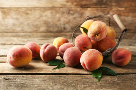 Ripe peaches in basket on wooden backgroundの写真素材