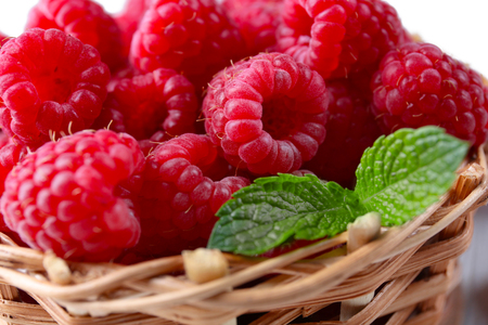 Fresh red raspberries in wicker basket, closeup