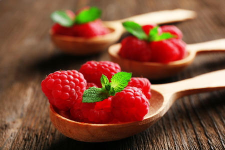 Fresh red raspberries in spoons on wooden table, closeupの写真素材