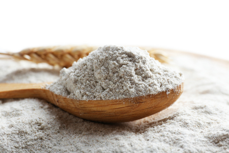 Wooden spoon on white flour backgroundの写真素材