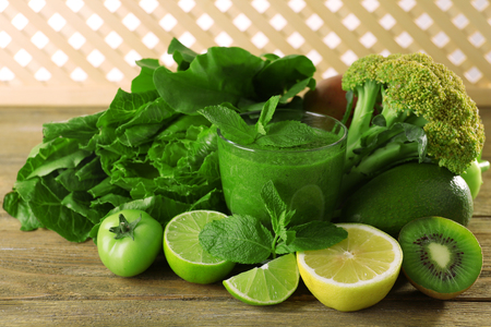 Green healthy juice with fruits and vegetables on wooden table close upの写真素材