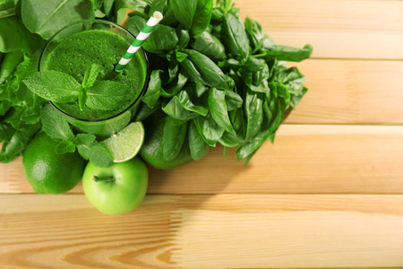 Green healthy juice with fruits and herbs on wooden table close upの写真素材