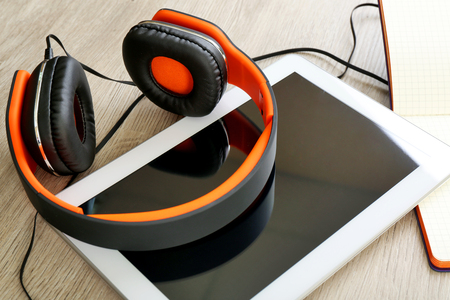 Headphones with tablet and notebook on wooden table close upの写真素材
