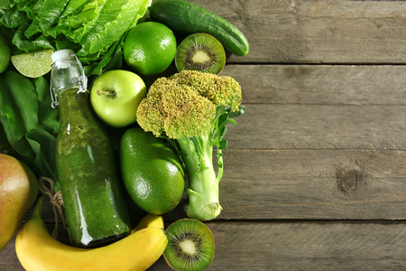 Green healthy juice with fruits and vegetables on wooden table close upの写真素材