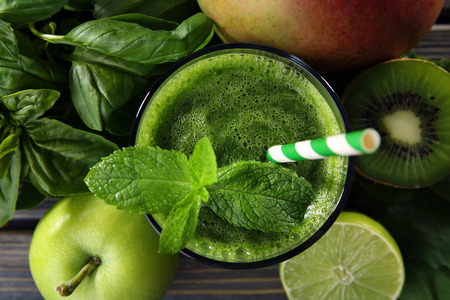 Green healthy juice with fruits and herbs on table close upの写真素材