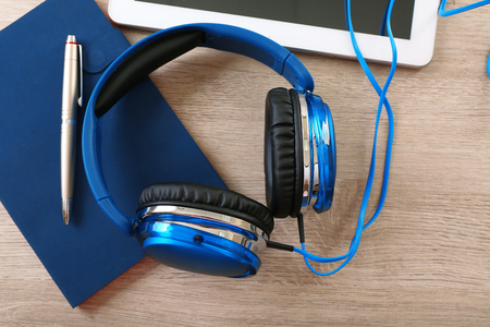 Headphones with tablet and notebook on wooden table close upの写真素材