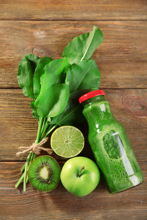 Green healthy juice with fruits and herbs on wooden table close upの写真素材