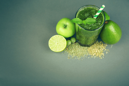 Green healthy juice with fruits and spices on gray backgroundの写真素材